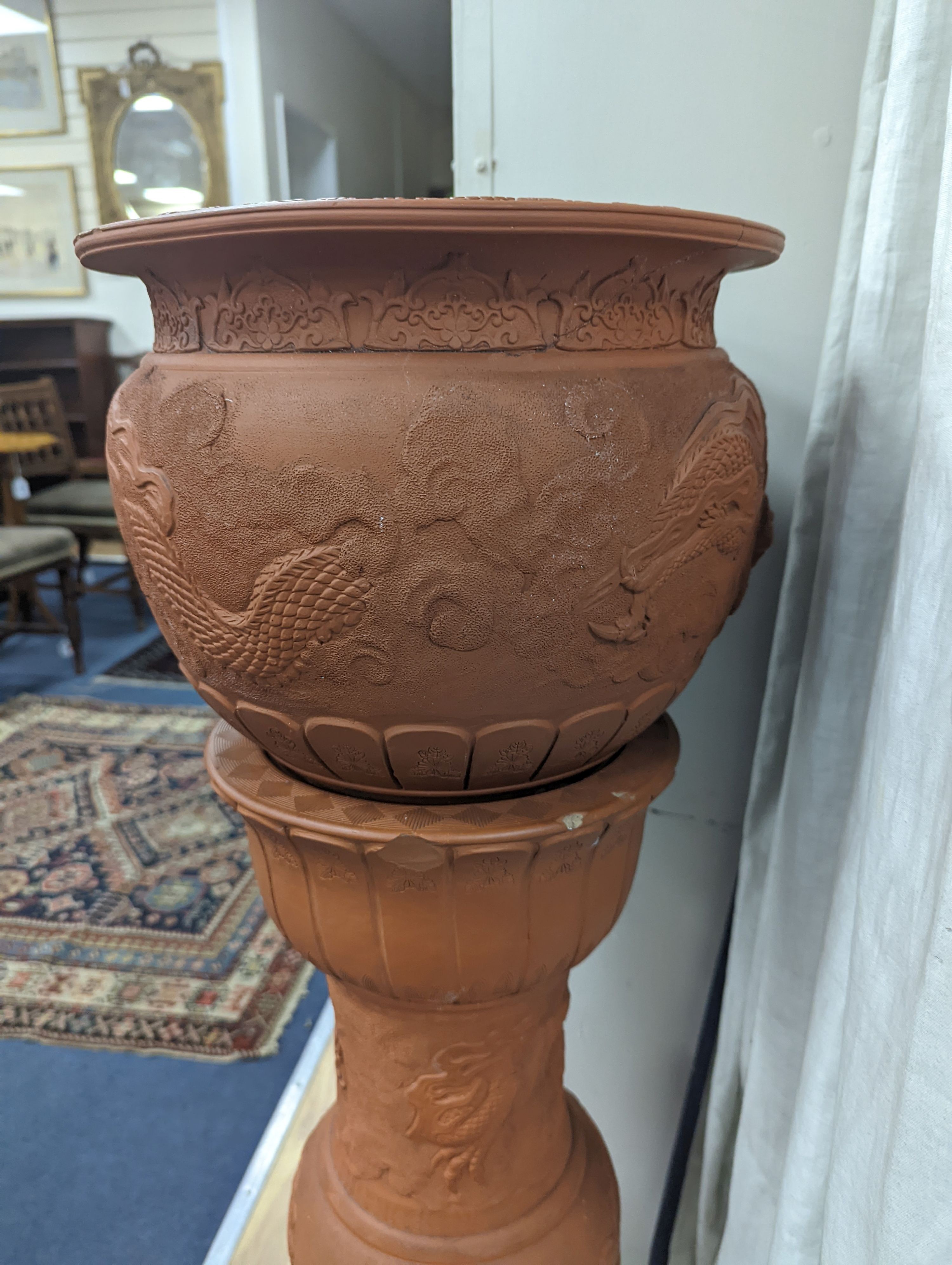 A Chinese earthenware jardiniere on stand moulded with dragons. Height 99 cms.